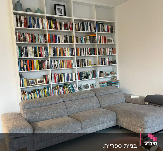 ספה אפורה מול מדפי ספרים מלאים